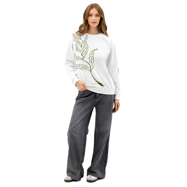 Woman wearing a white sweatshirt with a green leaf design and gray pants on a white background