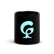 A large graphic letter G printed in bright aqua on a black glossy ceramic mug
