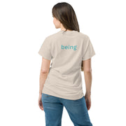 Person wearing a beige t-shirt with 'being' printed on the back, standing against a white background