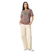 Woman wearing a blush colored t-shirt with a green graphic heart on a blush background