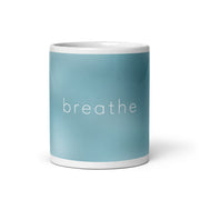 Text 'breathe' printed on a sky blue and clouds white glossy ceramic mug